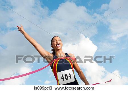 Stock Image - Female athlete crossing the finish line. Fotosearch