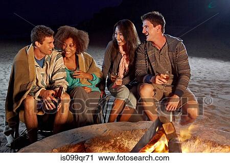 Stock Image - Friends having beach party at night. Fotosearch