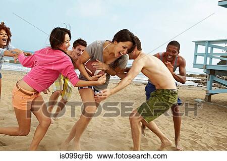 Friends on beach playing rugby View Large Photo Image Stock Image - Friends on beach playing rugby. Fotosearch