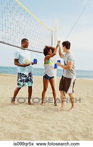 Friends on beach with volleyball and net View Large Photo Image Stock Photo - Friends on beach with volleyball and net. Fotosearch