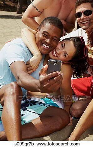 Friends photographing themselves on beach View Large Photo Image Stock Image - Friends photographing themselves on beach. Fotosearch