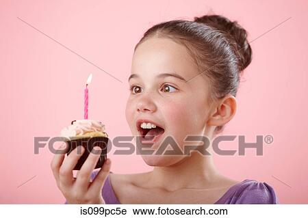Girl holding cupcake with candle View Large Photo Image Stock Image - Girl holding cupcake with candle. Fotosearch
