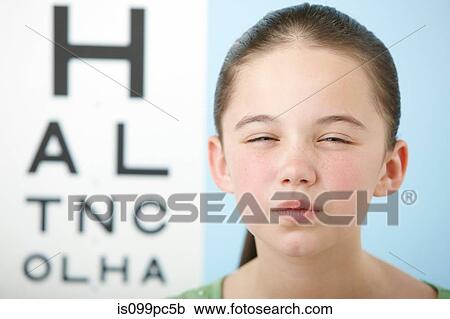 Girl squinting with eye chart in background View Large Photo Image Stock Image - Girl squinting with eye chart in background. Fotosearch