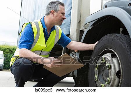 Man checking truck tire View Large Photo Image Stock Image - Man checking truck tire. Fotosearch
