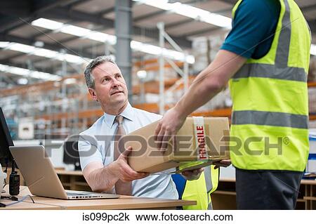 Stock Image - Man delivering cardboard box to another man. Fotosearch