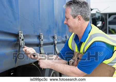 Stock Image - Man fastening truck straps. Fotosearch