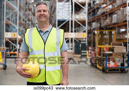 Man holding hard hat in warehouse, portrait View Large Photo Image Stock Image - Man holding hard hat in warehouse, portrait. Fotosearch