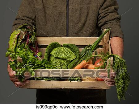 Picture - Man holding wooden crate of vegetables. Fotosearch