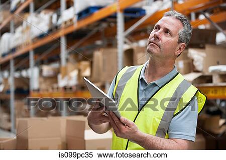 Man in warehouse using digital tablet View Large Photo Image Stock Photography - Man in warehouse using digital tablet. Fotosearch