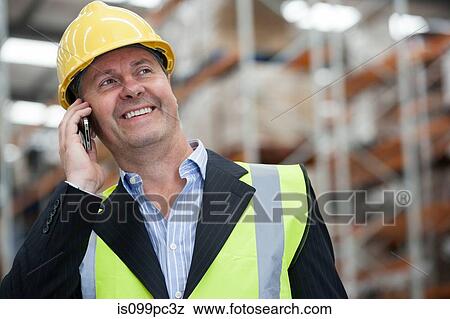 Man on cell phone in warehouse, portrait View Large Photo Image Stock Photo - Man on cell phone in warehouse, portrait. Fotosearch