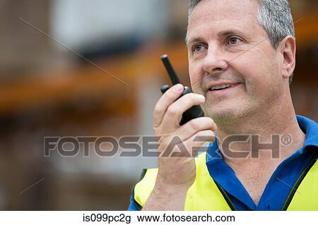 Stock Image - Man on walkie talkie, portrait. Fotosearch