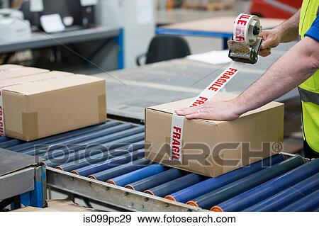 Stock Photo - Man packing cardboard box in warehouse. Fotosearch