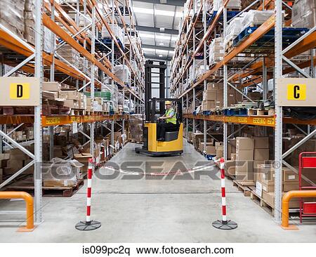 Stock Photography - Man transporting stock in distribution warehouse. Fotosearch