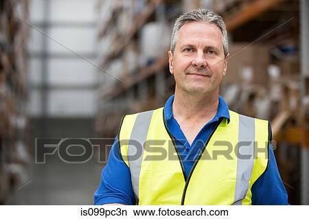 Man wearing high visibility clothing in warehouse, portrait View Large Photo Image Picture - Man wearing high visibility clothing in warehouse, portrait. Fotosearch