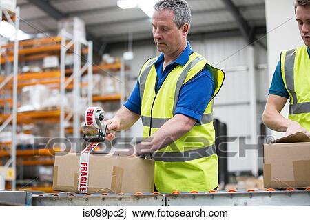 Men packing cardboard box in warehouse View Large Photo Image Stock Image - Men packing cardboard box in warehouse. Fotosearch