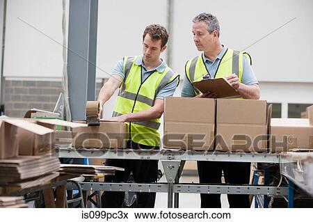 Men packing cardboard box in warehouse View Large Photo Image Stock Photo - Men packing cardboard box in warehouse. Fotosearch
