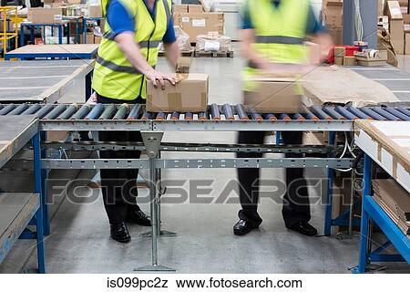 Men passing cardboard boxes along conveyor belt View Large Photo Image Stock Photo - Men passing cardboard boxes along conveyor belt. Fotosearch