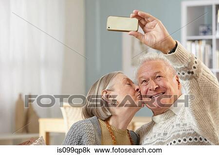 Stock Image - Senior couple photographing themselves with smartphone. Fotosearch