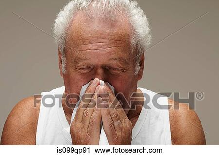 Stock Image - Senior man blowing nose. Fotosearch