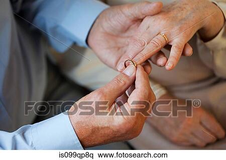 Senior man placing wedding ring on senior womans finger View Large Photo Image Stock Photography - Senior man placing wedding ring on senior womans finger. Fotosearch
