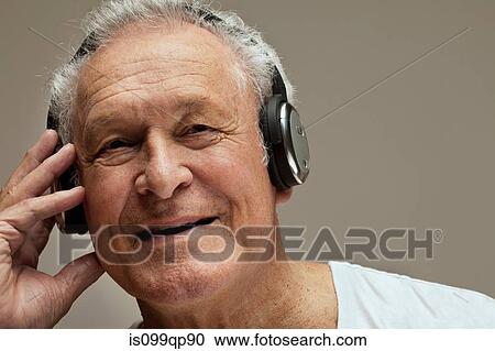 Stock Image - Senior man wearing headphones, portrait. Fotosearch