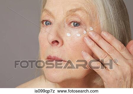 Stock Photo - Senior woman applying eye cream. Fotosearch