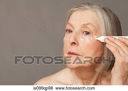 Stock Photo - Senior woman applying eye cream. Fotosearch