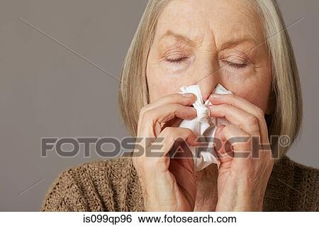 Stock Photograph - Senior woman blowing nose. Fotosearch