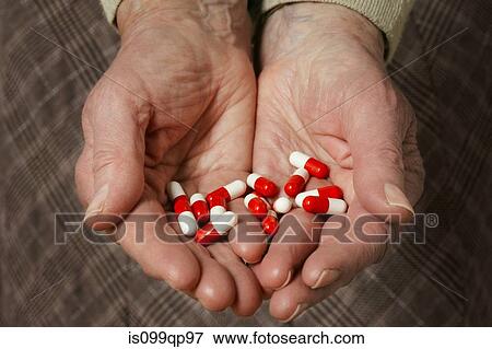 Stock Photo - Senior woman holding capsules. Fotosearch