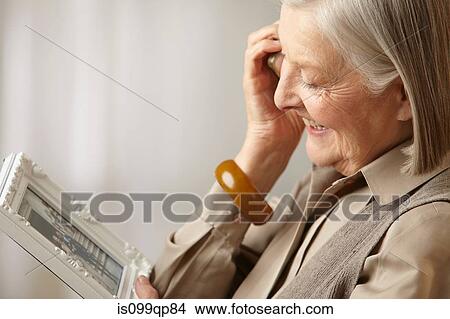 Picture - Senior woman holding picture frame. Fotosearch