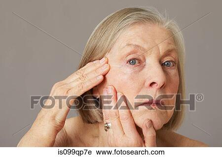 Stock Image - Senior woman touching face. Fotosearch