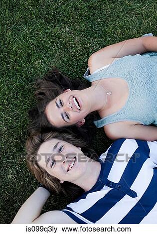 Teenage couple lying on grass from above View Large Photo Image Stock Photo - Teenage couple lying on grass from above. Fotosearch