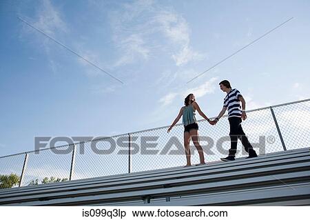 Teenage couple walking on bleachers View Large Photo Image Stock Photography - Teenage couple walking on bleachers. Fotosearch