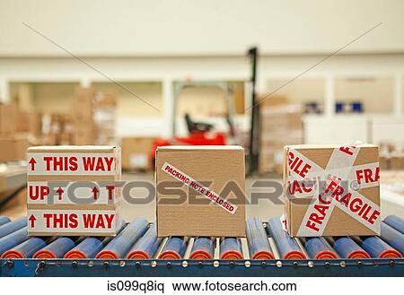 Stock Photography - Three cardboard boxes with parcel tape on conveyor belt. Fotosearch