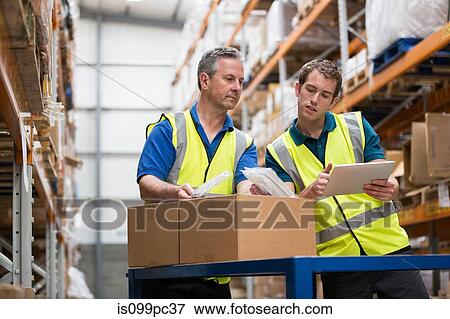 Two men checking stock in warehouse View Large Photo Image Stock Photo - Two men checking stock in warehouse. Fotosearch