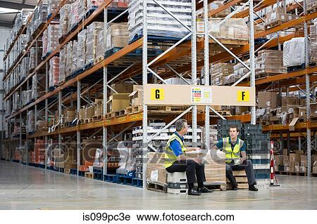 Stock Image - Two men having tea break in warehouse. Fotosearch