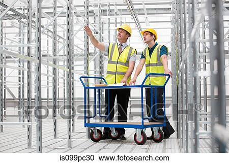 Two men in empty warehouse with trolley View Large Photo Image Stock Image - Two men in empty warehouse with trolley. Fotosearch