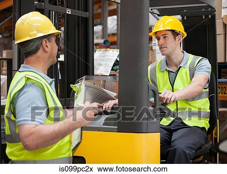 Two men in warehouse, one on forklift truck View Large Photo Image Stock Photo - Two men in warehouse, one on forklift truck. Fotosearch