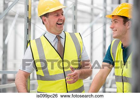 Stock Photograph - Two men laughing in warehouse. Fotosearch
