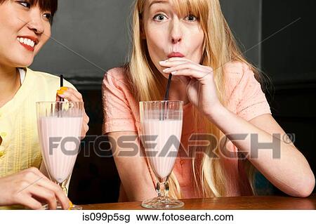 Two women drinking milkshake View Large Photo Image Stock Image - Two women drinking milkshake. Fotosearch