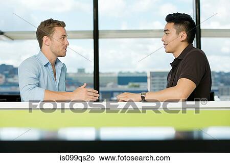 Two young businessmen talking View Large Photo Image Picture - Two young businessmen talking. Fotosearch