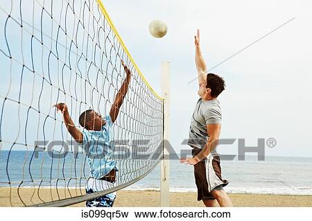 Stock Photo - Two young men playing beach volleyball. Fotosearch