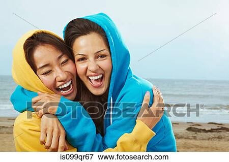 Two young women in hooded tops on beach View Large Photo Image Stock Photo - Two young women in hooded tops on beach. Fotosearch