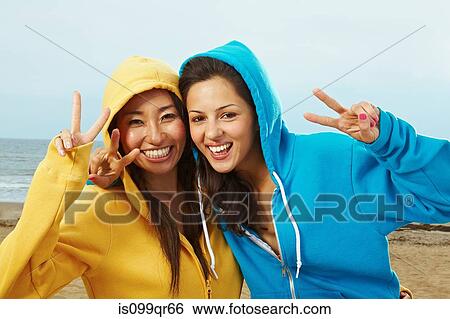 Two young women in hooded tops on beach View Large Photo Image Stock Photograph - Two young women in hooded tops on beach. Fotosearch