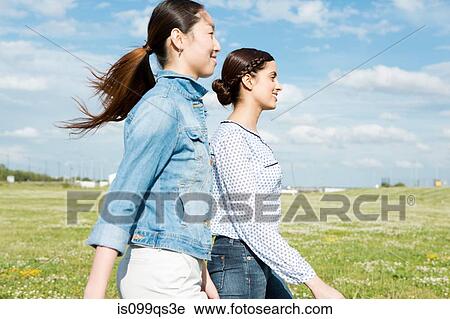 Stock Image - Two young women walking in field. Fotosearch