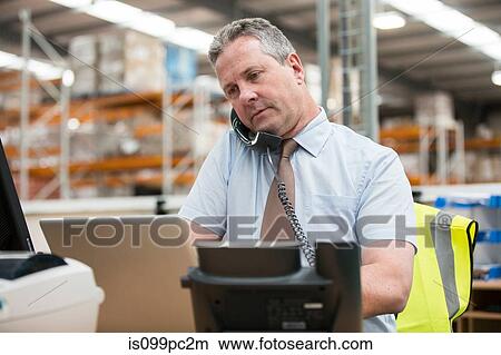Warehouse manager on the phone View Large Photo Image Picture - Warehouse manager on the phone. Fotosearch