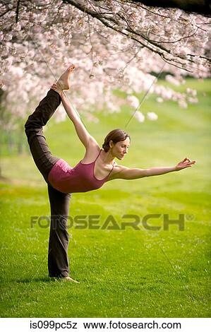Stock Photo - Woman in dancer yoga position in park. Fotosearch