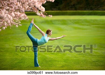 Woman in standing bow yoga position in park View Large Photo Image Stock Image - Woman in standing bow yoga position in park. Fotosearch