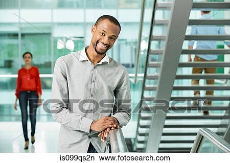 Young businessman by stairs in office View Large Photo Image Picture - Young businessman by stairs in office. Fotosearch