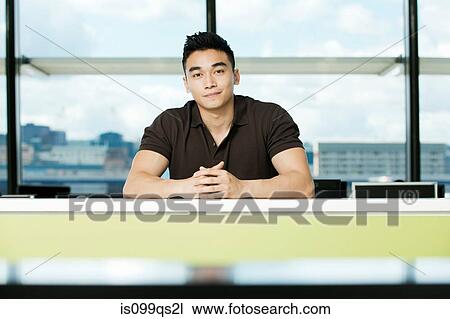Stock Image - Young businessman sitting at desk. Fotosearch